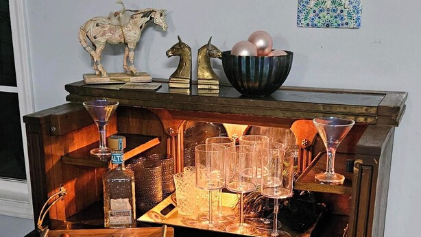 Un espace bar avec un comptoir en bois, des verres, des bouteilles et des objets décoratifs.