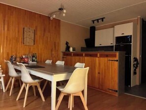 A dining area with a wooden wall, a table, and chairs. - Large apartment with magnificent view 100 m from the slopes (Orcières)