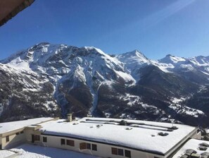 A mountain view with a building featuring a flat roof and multiple windows. - Large apartment with magnificent view 100 m from the slopes (Orcières)