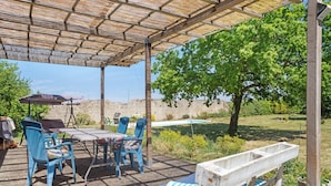 Eine Terrasse im Freien mit Tisch, Stühlen, einer Holzbank und einer Pergola.
