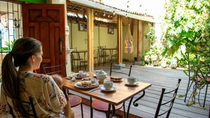 Eine Terrasse mit einem Holztisch, Stühlen und einer hängenden Dekoration.