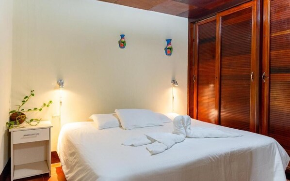 Una camera d'albergo con un letto, un comodino, luci a parete e un armadio.
