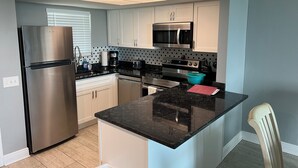 Una cocina moderna con electrodomésticos de acero inoxidable, una isla central y un microondas sobre el horno.