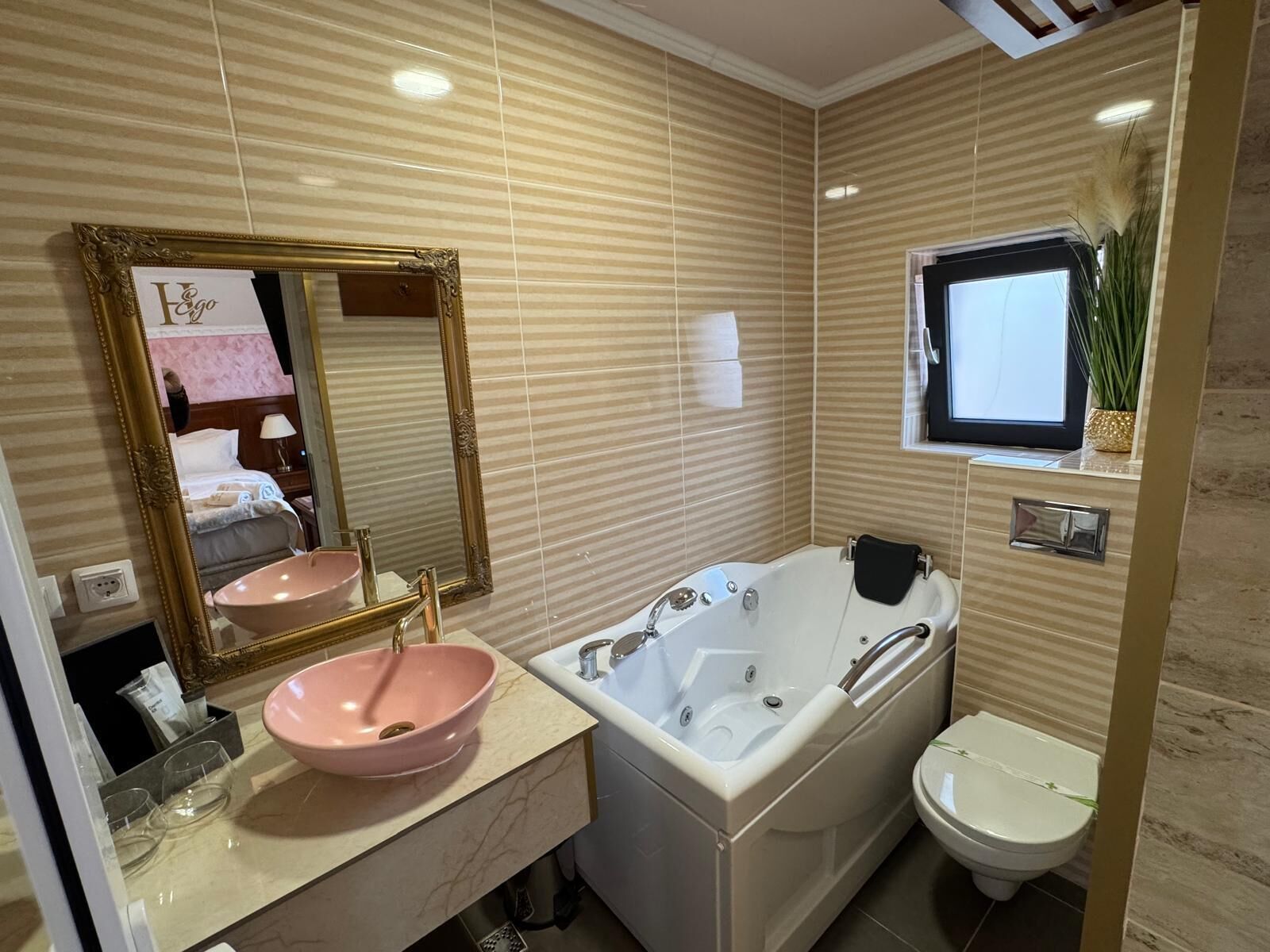 Een moderne badkamer met een wastafel, een grote spiegel, een bad en een toilet.