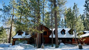 A log cabin with a snow-covered roof, surrounded by tall pine trees. - Evergreen (Big Bear Lake)