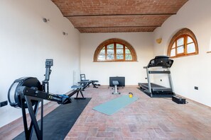 Ein Fitnessraum mit Trainingsgeräten, Laufband und Yogamatte.