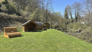 A campsite with wooden cabins, a bench, and a grassy area. - Eifelhutte auf dem Campingpark (Waxweiler)
