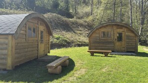 Two wooden cabins with pitched roofs, each featuring a door and window, and a picnic table in front of one. - Eifelhutte auf dem Campingpark (Waxweiler)