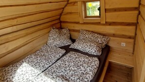 A wooden cabin room with a bed, pillows, a window, and a small skylight. - Eifelhutte auf dem Campingpark (Waxweiler)