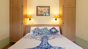 Un dormitorio con una cama, dos lámparas de pared, una obra de arte floral enmarco y armarios de madera.