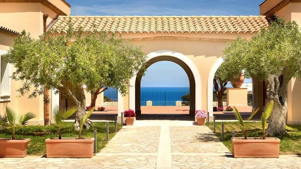 Un sendero que lleva a un arco con vista al mar.