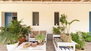 A covered outdoor seating area with potted plants, a white bench, and a sofa with patterned cushions. - Peaceful Countryside Villa - 8 Mins to Guidaloca Beach & Scopello (Sicilia)