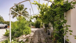 A garden pathway with a pergola, plants, and a white car parked nearby. - Peaceful Countryside Villa - 8 Mins to Guidaloca Beach & Scopello (Sicilia)