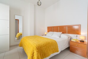 Ein Schlafzimmer mit Bett, Nachttisch, Lampe und Kleiderschrank.