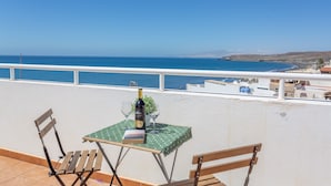 Un balcón con una mesa preparada para dos personas, una botella de vino y un libro.