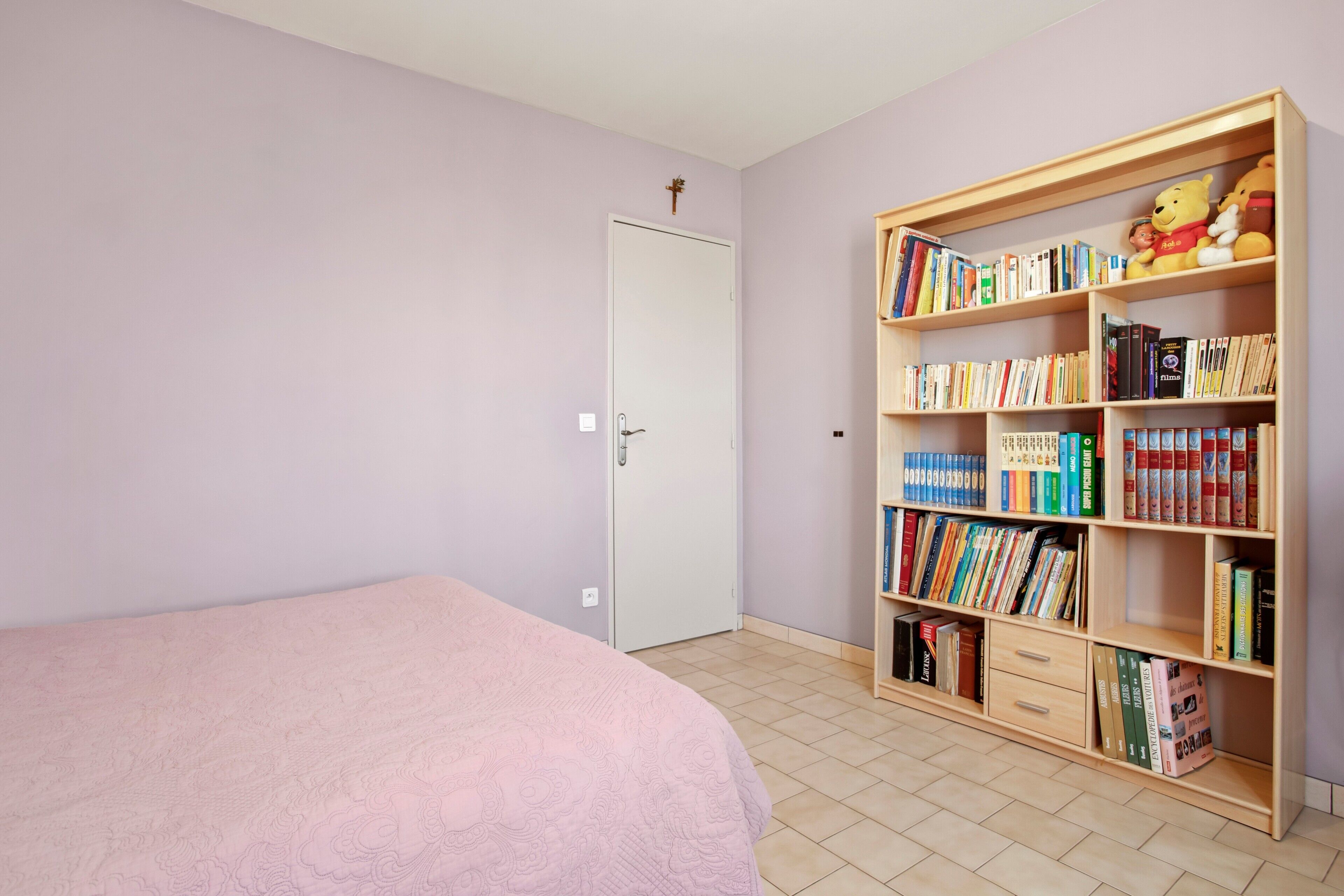 A bedroom with a bed, a bookshelf, and a door.