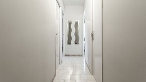 Un couloir aux murs blancs, doté d’un sol carrelé et d’une porte au motif ondulé original.