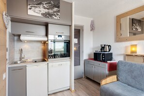 Une cuisine compacte équipée d’un lave-vaisselle, d’un four et d’un four à micro-ondes.