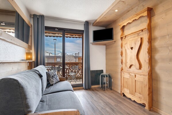 Une chambre moderne avec un canapé, un téléviseur fixé au mur et un meuble en bois.
