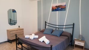 Un llit amb capçalera, una taula de nit, un mirall fixat a la paret i un quadre a la paret.