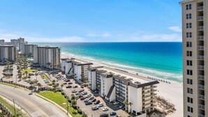 Ein Hotel an der Küste mit mehreren Etagen, einem Parkplatz und Blick auf den Strand.
