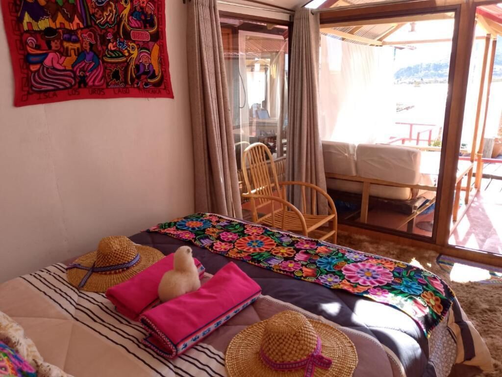 A bed with a colorful blanket, a straw hat, and a pink pillow.