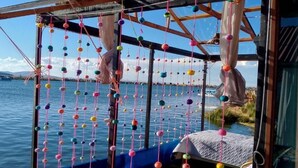 A room with a view of the water, a bed, and a hanging decoration. - Uros TITIKAKA the Best lodge  (Puno)