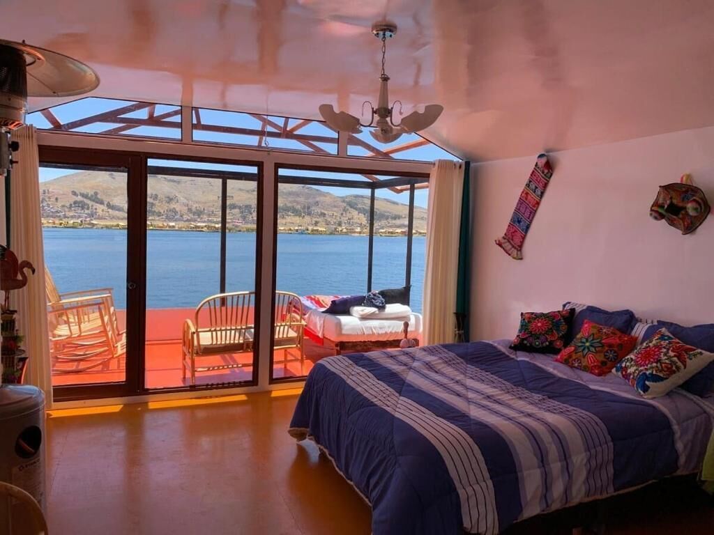 Quarto com cama, cadeira, janela e vista para a água.