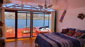 Une chambre à coucher avec un lit, une chaise, une fenêtre et une vue sur l’eau.
