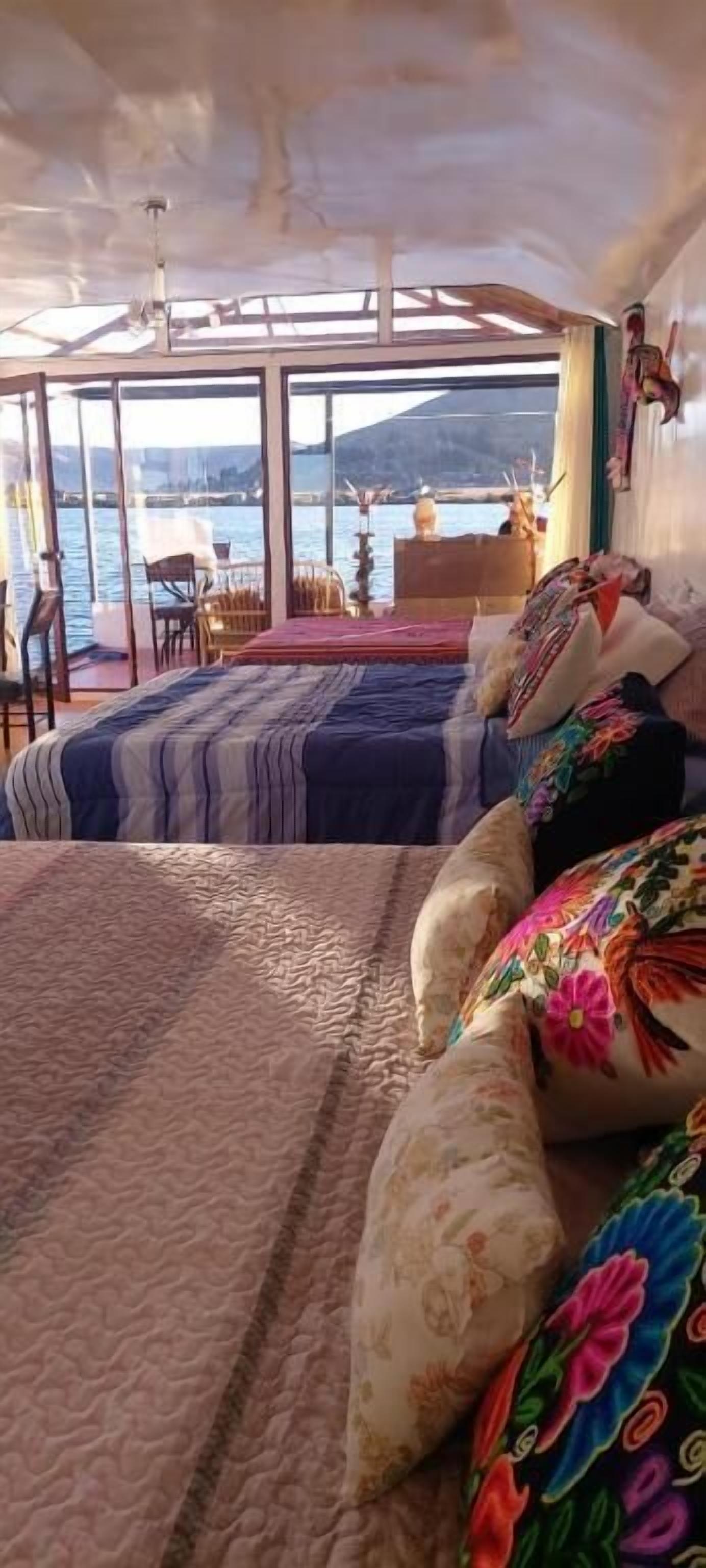 A bedroom with a large bed, a view of the water, and a balcony with chairs.