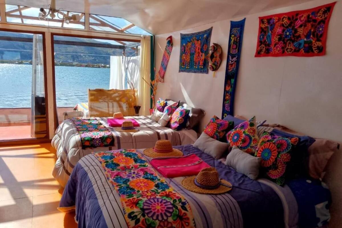 Una habitación con dos camas, mantas de colores y vista al agua.