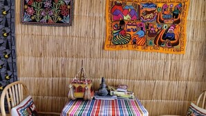 A room with a woven wall, a colorful striped tablecloth, and two chairs. - Uros TITIKAKA the Best lodge  (Puno)