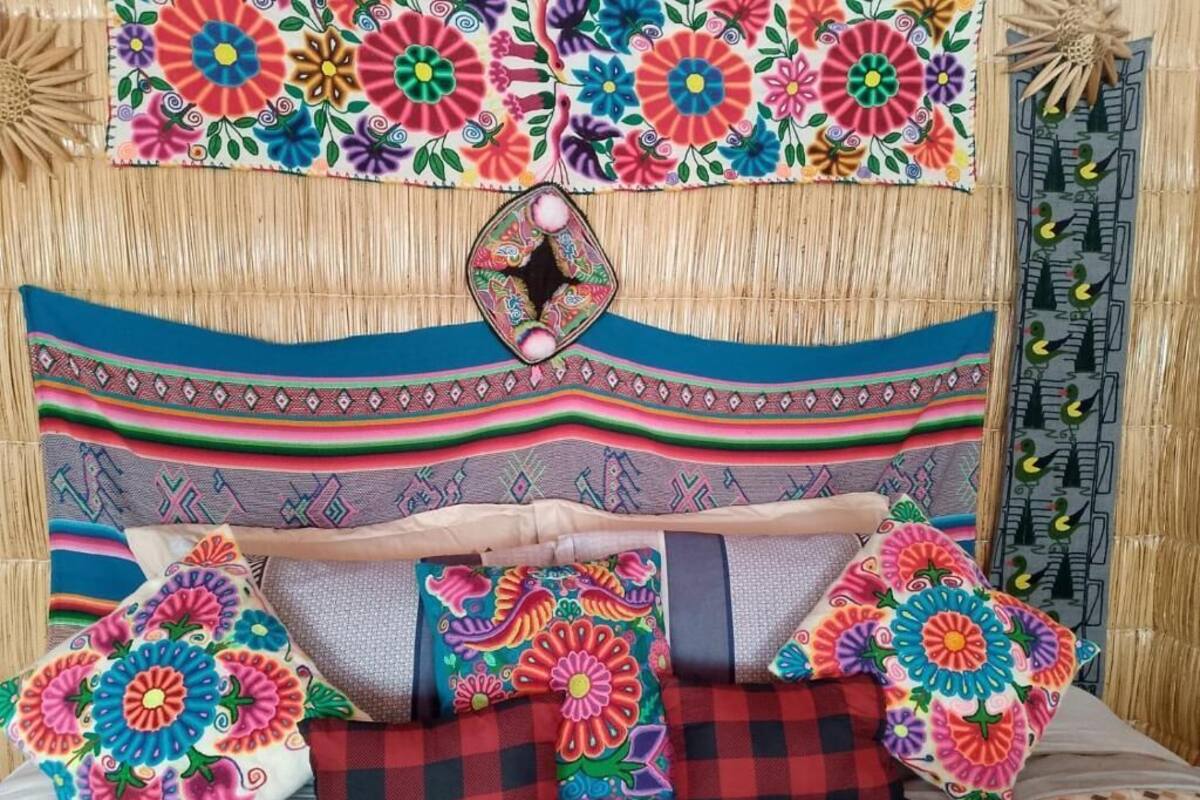Una cama con almohadas coloridas y un cabecero estampado.