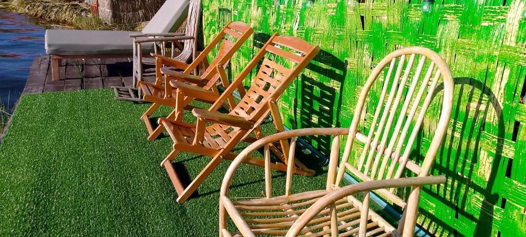 Zona de piscina con sillones de madera y una tumbona blanca.