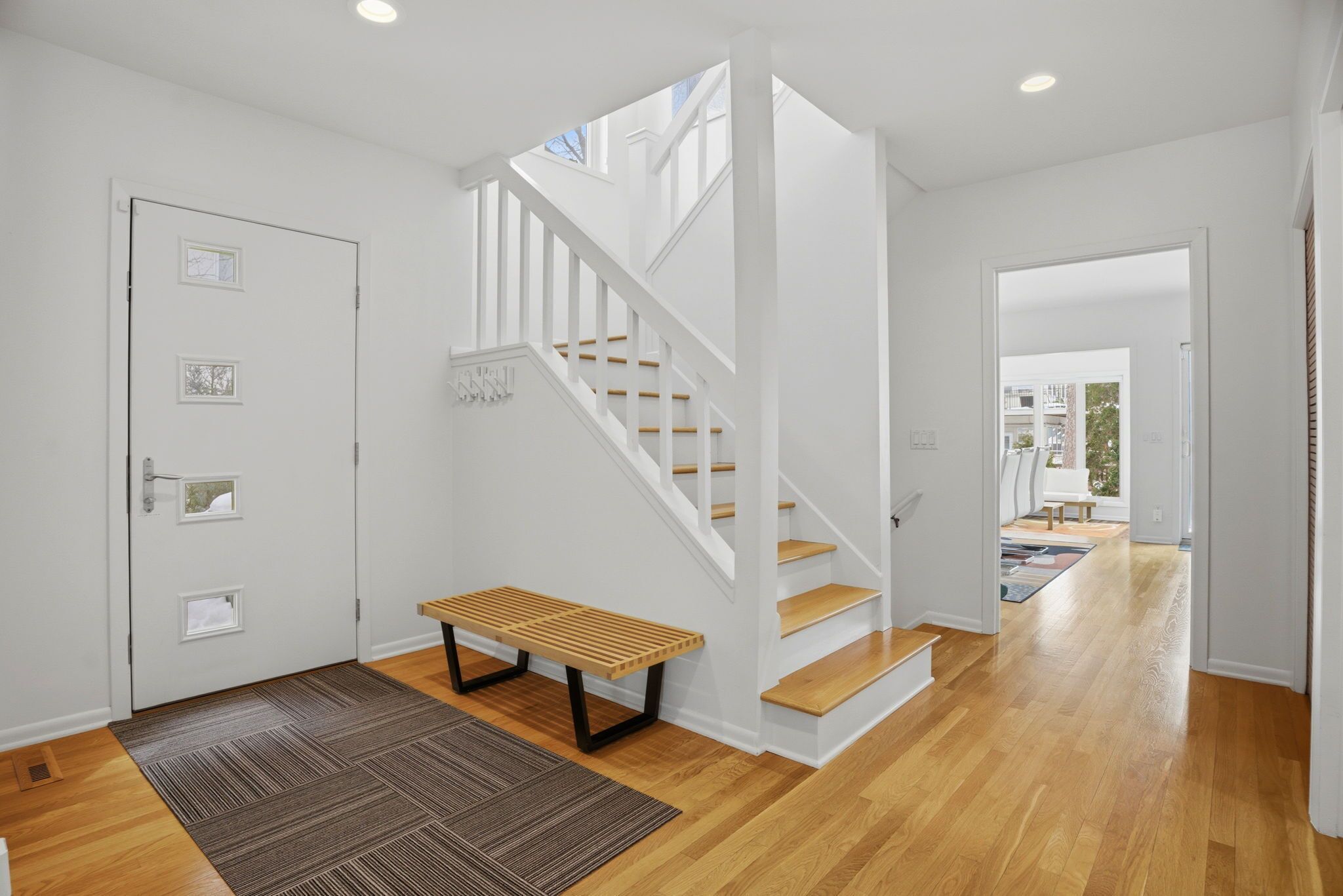 Een modern interieur met een trap, houten vloer en een bankje.