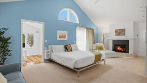 A bedroom with a bed, a chair, a fireplace, and a ceiling fan. - Lake of the Isles Retreat (Minneapolis)