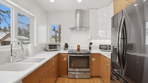 A modern kitchen with stainless steel appliances, wooden cabinets, and a window providing a view of the outside. - Lake of the Isles Retreat (Minneapolis)