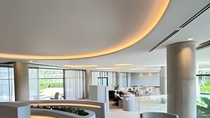Een moderne lobby met een gebogen receptiebalie, een zithoek en grote ramen.