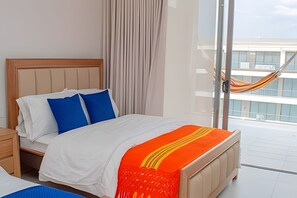 Ein Hotelzimmer mit Bett, Nachttisch, Fenster mit Blick auf ein Gebäude und einer Hängematte.