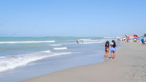 Een strand met mensen die langs de kust wandelen, parasols en ligbedden.