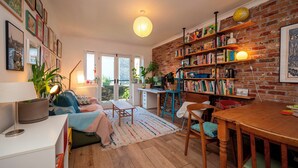 A cozy living room with a fireplace, a bookshelf, and a dining area. - Artist's apartment in St Johns - Pass the Keys (London)
