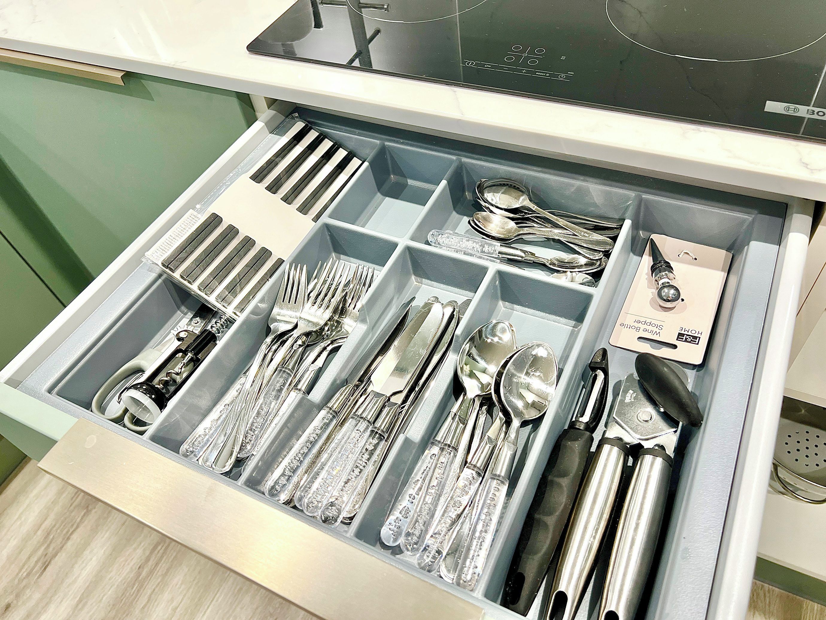 A drawer with compartments containing various kitchen utensils.