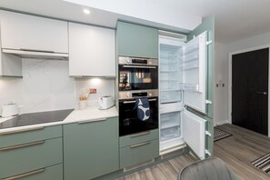 Une cuisine moderne équipée d’un four encastré, d’un réfrigérateur et d’un four à micro-ondes.