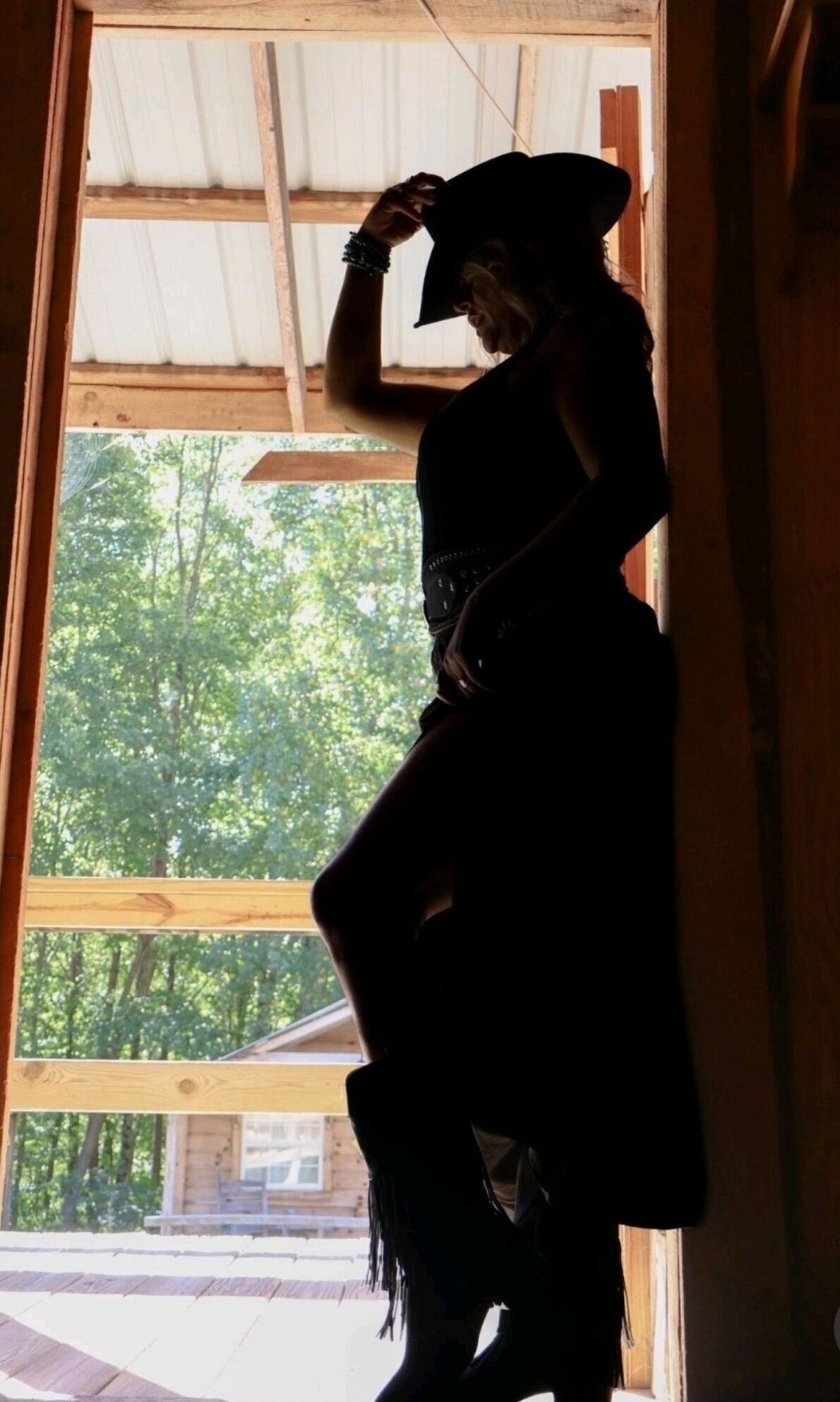 A silhouette of a person standing in a doorway with a view of trees outside.