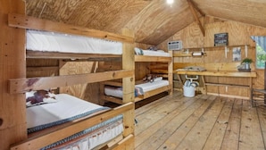 A rustic wooden cabin with bunk beds, a kitchenette, and a ceiling fan. - Step Into Your Own Western Town Cabins, Saloon, ATV Trails & Private Group Stays (Winfield)