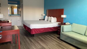 Ein Hotelzimmer mit Bett, Nachttischen, Schreibtisch, Stuhl und einer Couch.