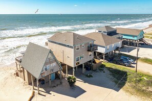 Ein Strandgrundstück mit mehreren Gebäuden, darunter ein Haus mit Balkon und einer in den Ozean ragenden Pier.