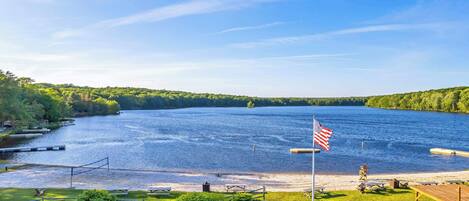 A river with a dock, picnic tables, and an American flag on a pole.