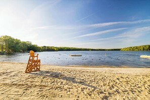 Ein Strand mit einem Holzstuhl und einem See.