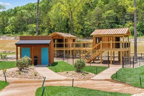 Une cabane en bois avec une véranda, un escalier et une zone délimitée par une clôture.